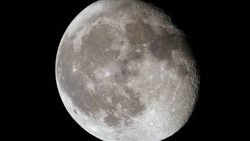 Zbliżenie na Księżyc z widocznymi kraterami i morzami księżycowymi na czarnym tle.