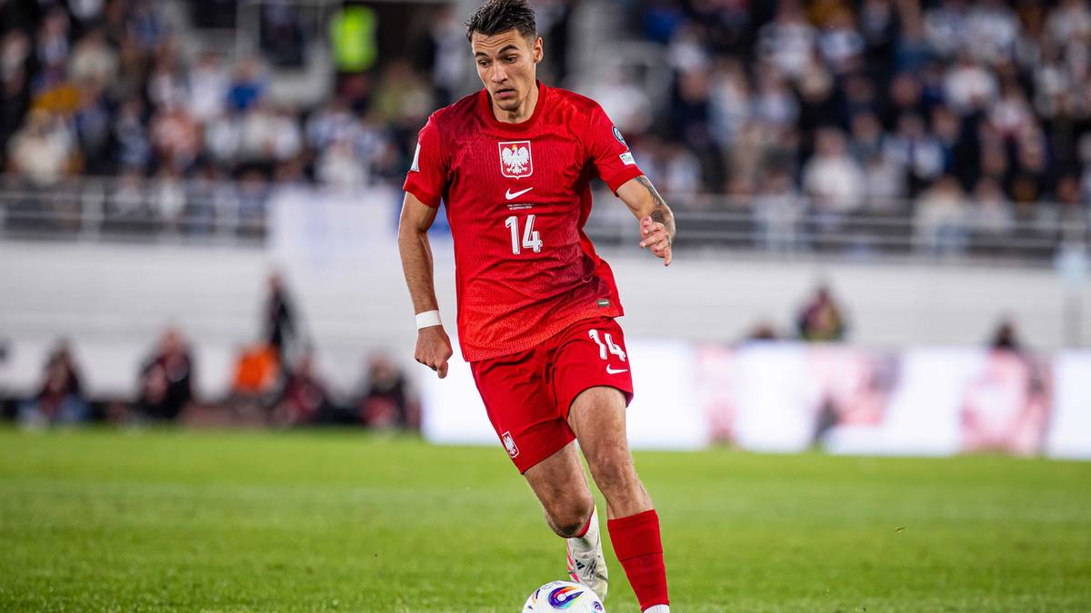 Piłkarz w czerwonej koszulce reprezentacji Polski z numerem 14, prowadzący piłkę.