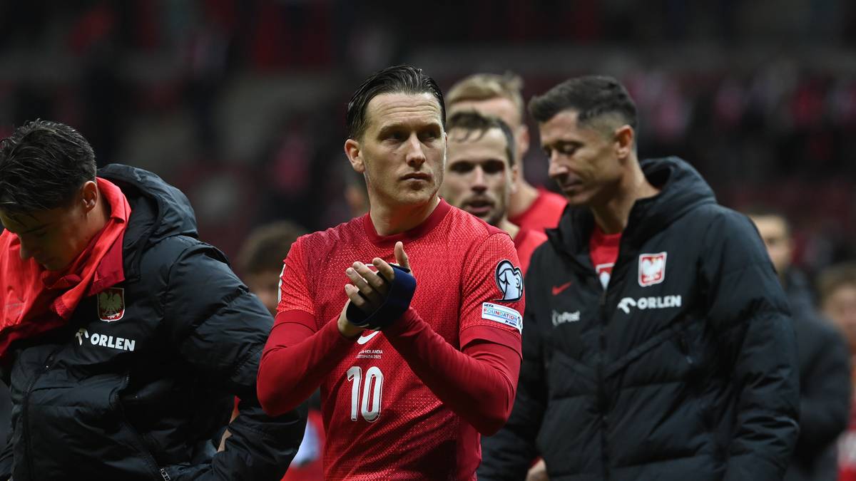 Piłkarze reprezentacji Polski w strojach meczowych, jeden z nich klaszcze.