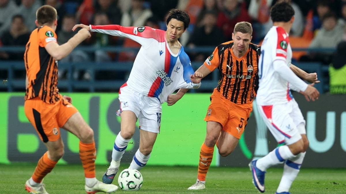 Piłkarze w akcji na boisku, jeden z nich pr&oacute;buje odebrać piłkę przeciwnikowi.