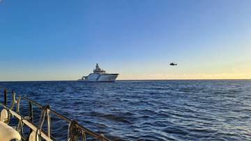 Widok statku towarowego na morzu przy zachodzącym słońcu.