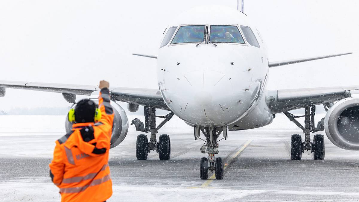 Pracownik lotniska kieruje samolot na pasie startowym.