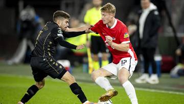 Dwóch piłkarzy walczących o piłkę na boisku.