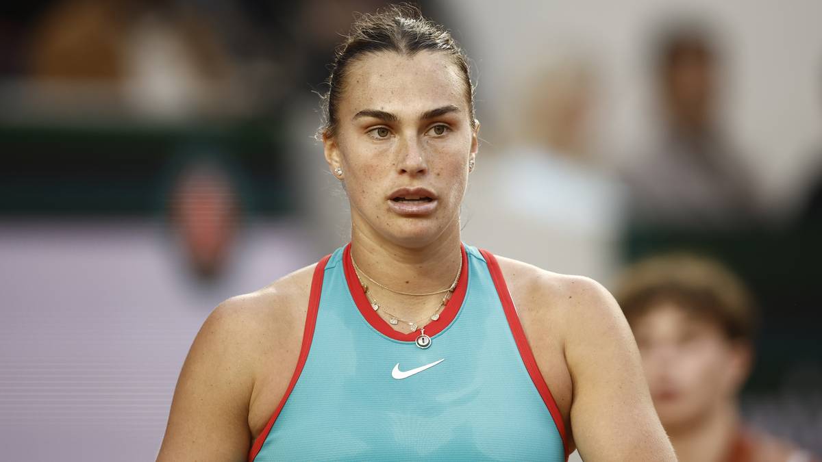 Portret tenisistki Aryny Sabalenki, zamyślonej, zdeterminowanej, na tle kortu tenisowego. Ubrana jest w turkusowy top sportowy z czerwonymi akcentami i naszyjnik.