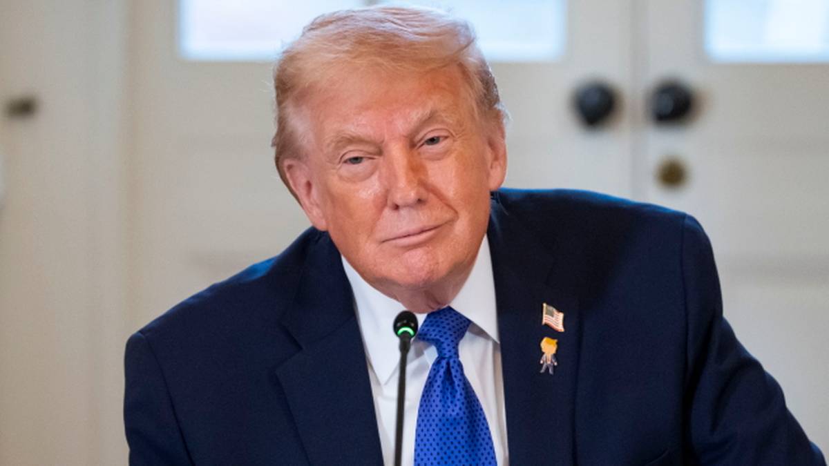 Donald Trump w ciemnym garniturze i niebieskim krawacie podczas spotkania.