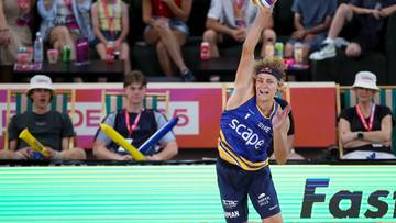 Siatkarz plażowy serwujący piłkę w trakcie meczu.