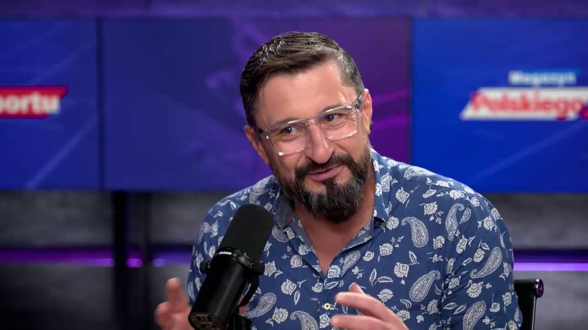 Ekspert Polsatu Sport Jakub Bednaruk w okularach i koszuli w niebieskie wzory, siedzi przed mikrofonem w studiu telewizyjnym.