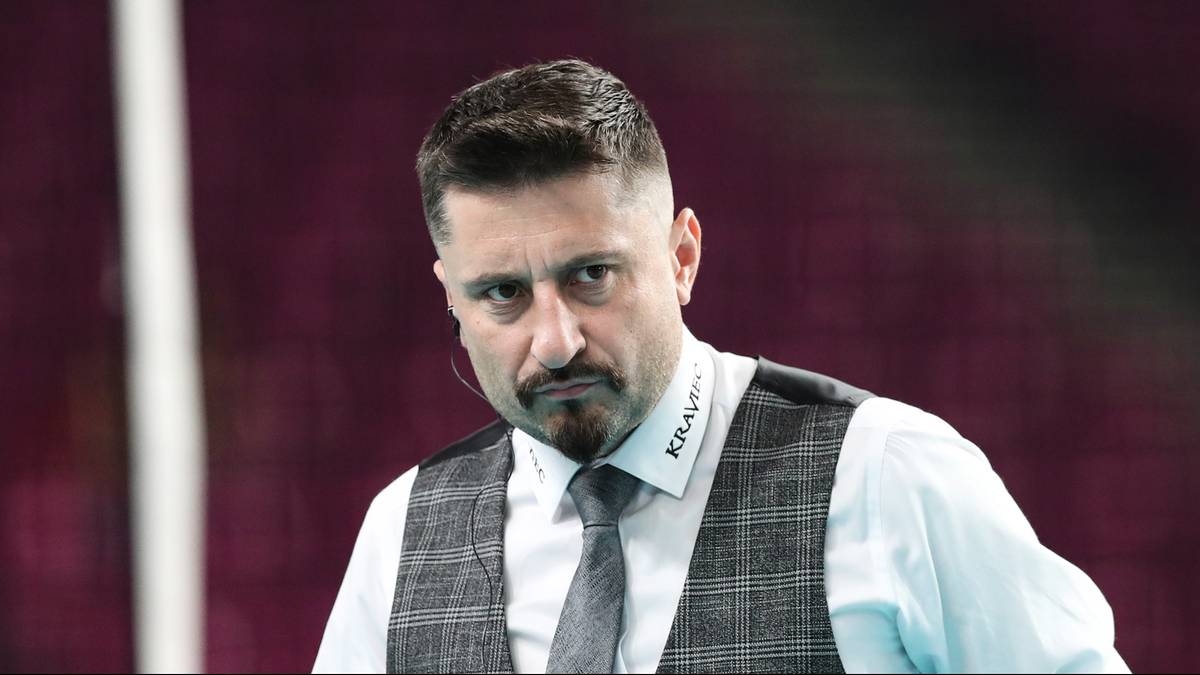 Portret Jakuba Bednaruka, trenera siatkówki, patrzącego w stronę obiektywu z poważnym wyrazem twarzy.