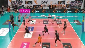 Drużyna siatkarzy JSW Jastrzębski Węgiel rozgrywa mecz przeciwko Barkom-Każany Lw&oacute;w. Zawodnicy są w ruchu na boisku, a publiczność obserwuje z trybun.