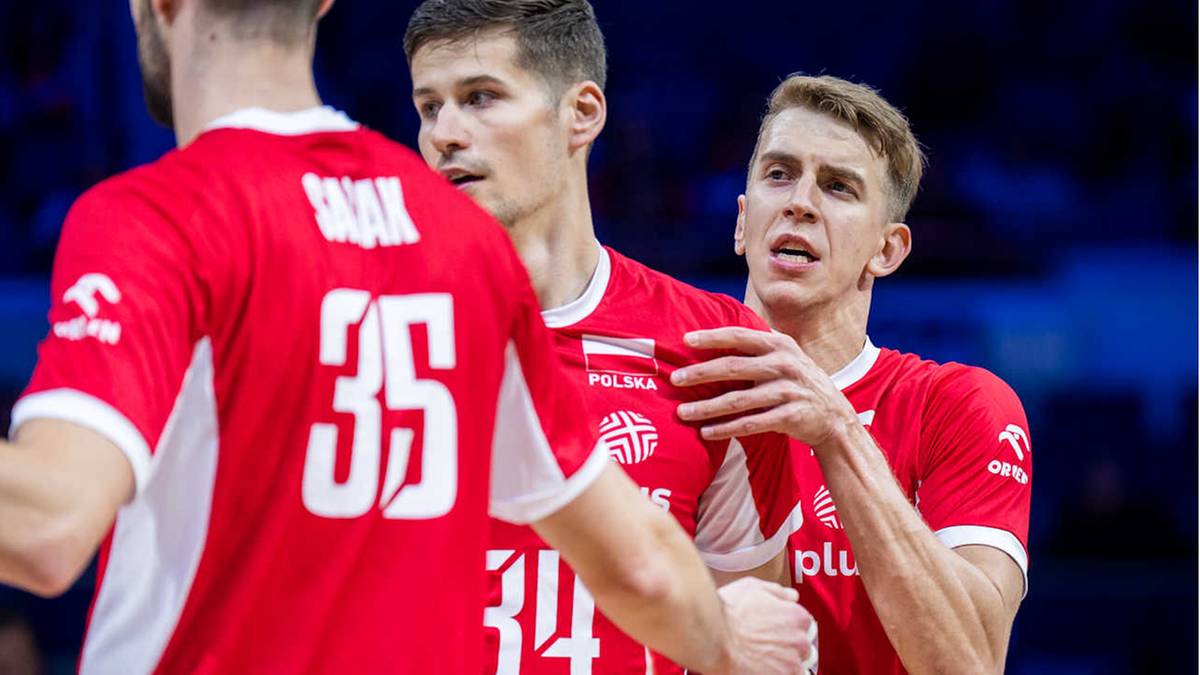 Trzech młodych mężczyzn w czerwonych koszulkach reprezentacji Polski w siatkówce. Dwóch z nich rozmawia ze sobą, trzeci jest odwrócony tyłem, ale jego koszulka z numerem 35 jest widoczna.