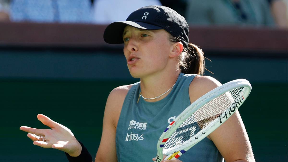 Tenisistka w czarnym stroju sportowym trzyma rakietę tenisową w prawej dłoni i wykonuje gest ręką.