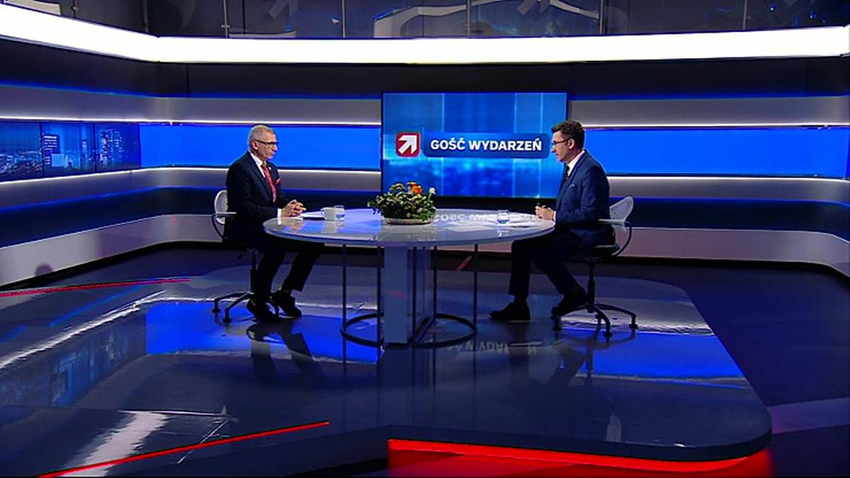 Dw&oacute;ch mężczyzn siedzi przy okrągłym stole w studiu telewizyjnym, na kt&oacute;rym wyświetlany jest napis "Gość Wydarzeń".