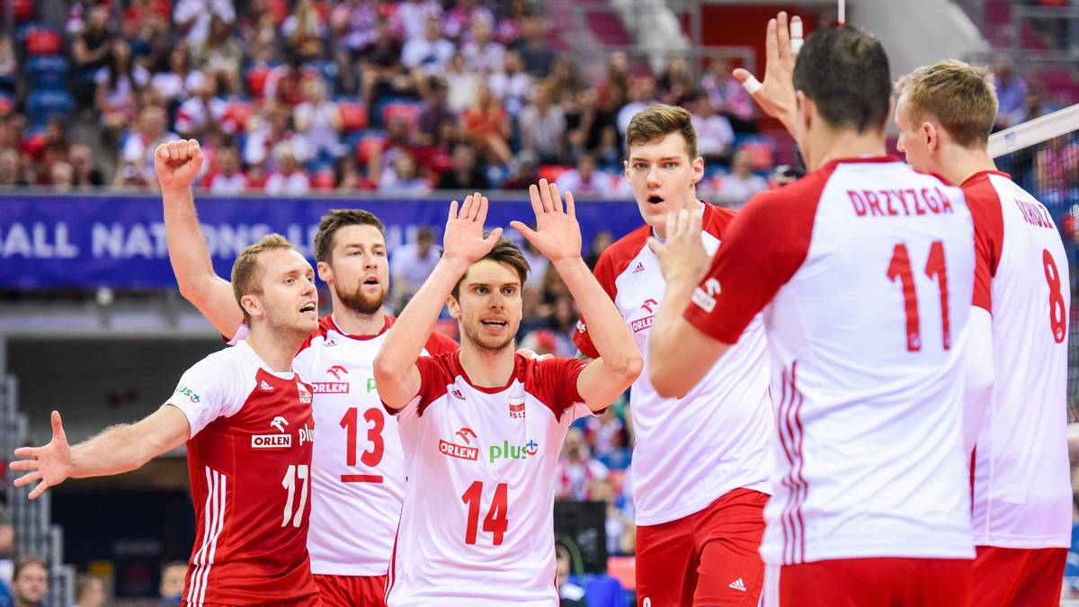 Sześciu zawodników w biało-czerwonych strojach siatkarskich cieszy się na boisku, machając rękami w stronę publiczności.