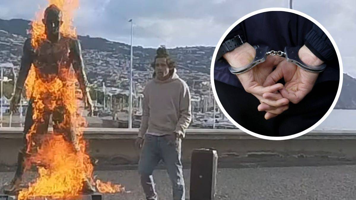 Pomnik Cristiano Ronaldo płonie, obok stoi mężczyzna.