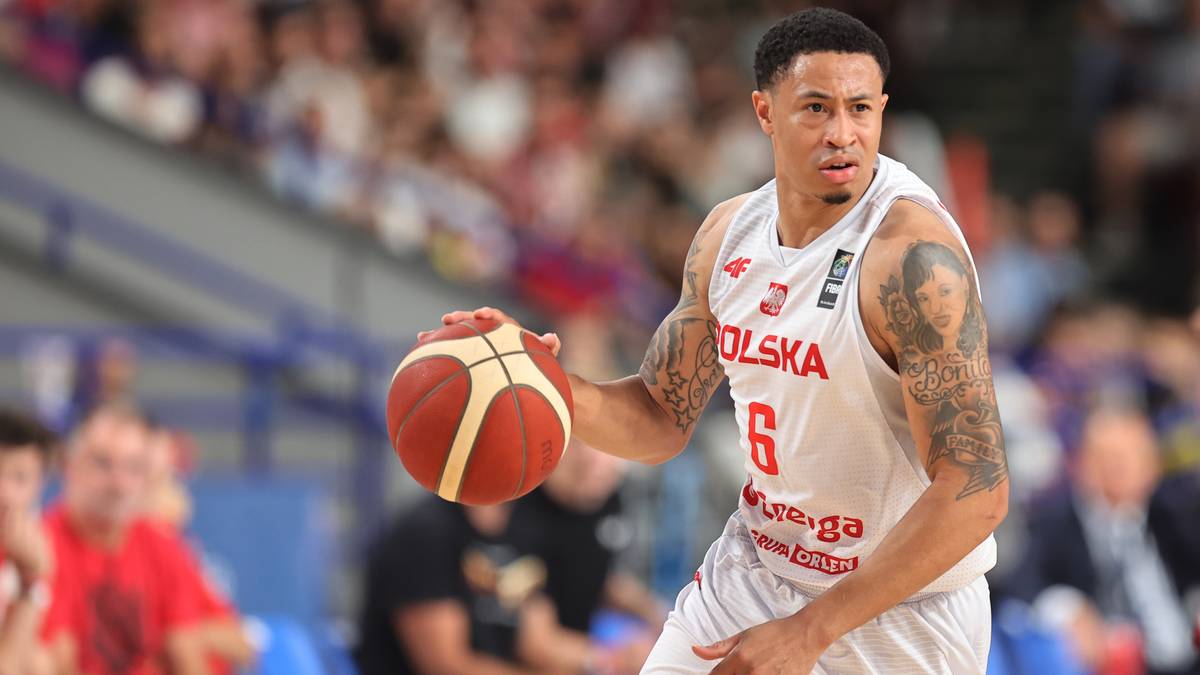 Gracz w białej koszulce z numerem 6 na plecach prowadzi piłkę do koszyk&oacute;wki w trakcie meczu.