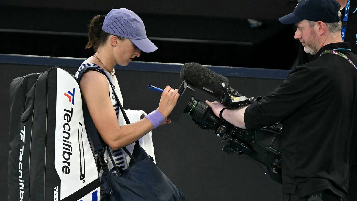 Iga Świątek z torbą tenisową i sprzętem filmowym na korcie.