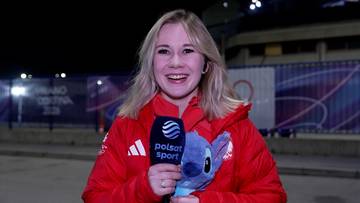 Jekatierina Kurakowa w czerwonej kurtce trzyma mikrofon Polsat Sport i pluszową zabawkę, uśmiechając się.