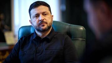 Wołodymyr Zełenski, prezydent Ukrainy, siedzi w fotelu w ciemnej koszuli.