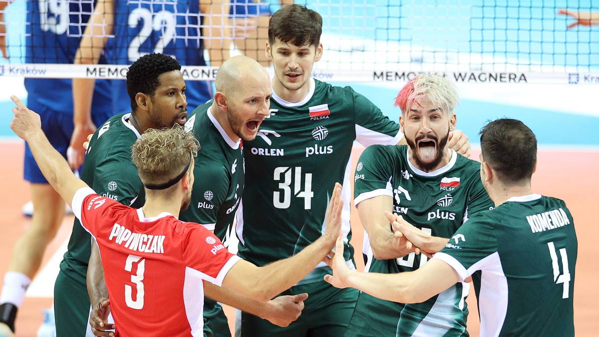 Drużyna siatkarzy w zielonych strojach cieszy się z wygranego meczu, jeden z zawodników w czerwonej koszulce jest w centrum uwagi.