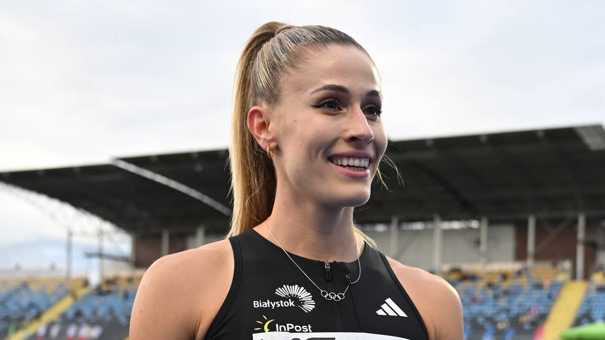 Uśmiechnięta młoda kobieta z blond włosami spiętymi w kucyk, ubrana w czarną koszulkę sportową z logo drużyny.