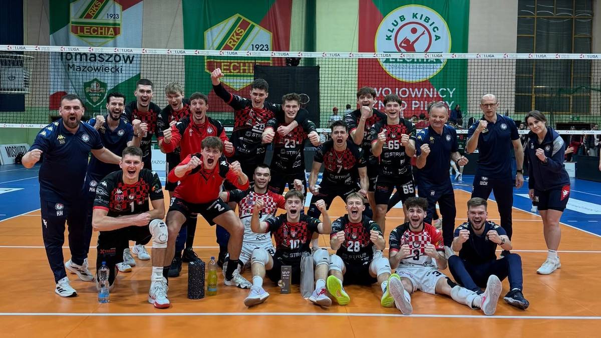 Drużyna siatkarska pozuje do zdjęcia na boisku.