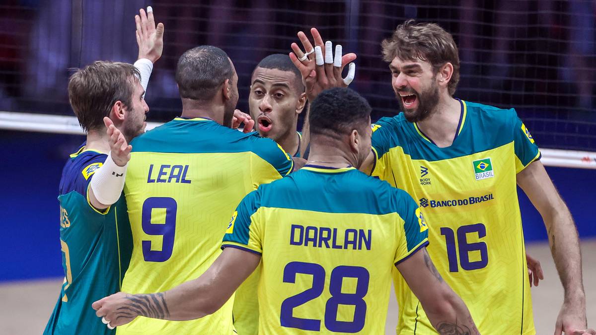 Grupa siatkarzy w ż&oacute;łto-zielonych strojach świętuje na boisku siatkarskim.