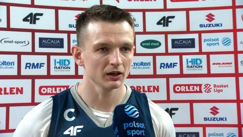 Grzegorz Grochowski udziela wywiadu na tle sponsor&oacute;w.