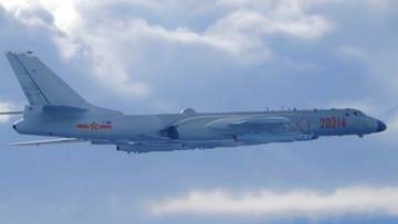 Chiński samolot wojskowy H-6K w locie na tle nieba z chmurami.