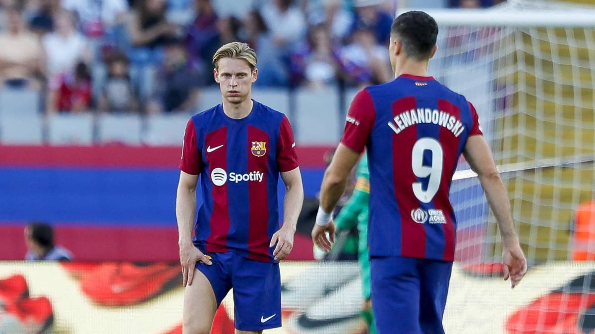 Piłkarze FC Barcelony Frenkie de Jong i Robert Lewandowski na boisku w strojach klubowych.