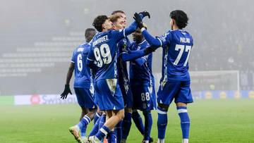 Piłkarze w niebieskich strojach świętują bramkę na boisku.