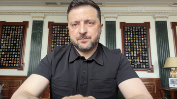 Wołodymyr Zełenski, prezydent Ukrainy, siedzi przy biurku i patrzy prosto w kamerę.