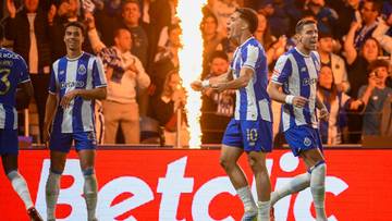 Piłkarze FC Porto w niebiesko-białych strojach świętują zdobycie bramki, na tle płomieni i kibic&oacute;w.