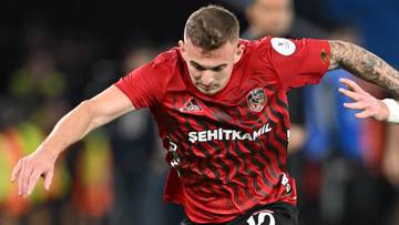 Piłkarze walczą o piłkę na boisku podczas meczu piłkarskiego.