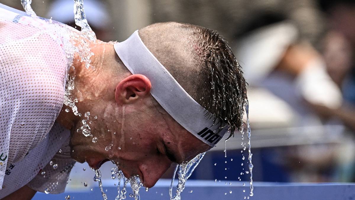 Zawodnik podczas zawodów sportowych polewa głowę wodą z wiadra.