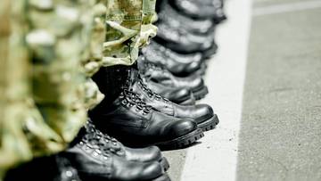 Nogi żołnierzy w butach wojskowych i spodniach moro ustawione w rzędzie.