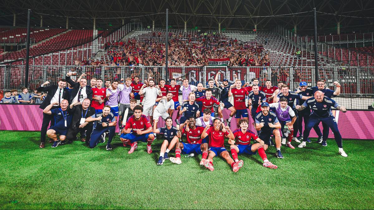 Drużyna Rakowa Częstochowa i sztab szkoleniowy pozują do zdjęcia na zielonej murawie stadionu, z kibicami w tle.