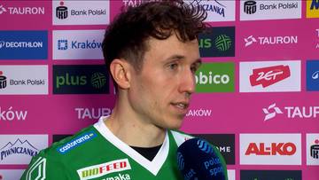 Zbliżenie na twarz Pawła Halaby w zielonej koszulce sportowej, z widocznymi logotypami sponsor&oacute;w na r&oacute;żowym tle.