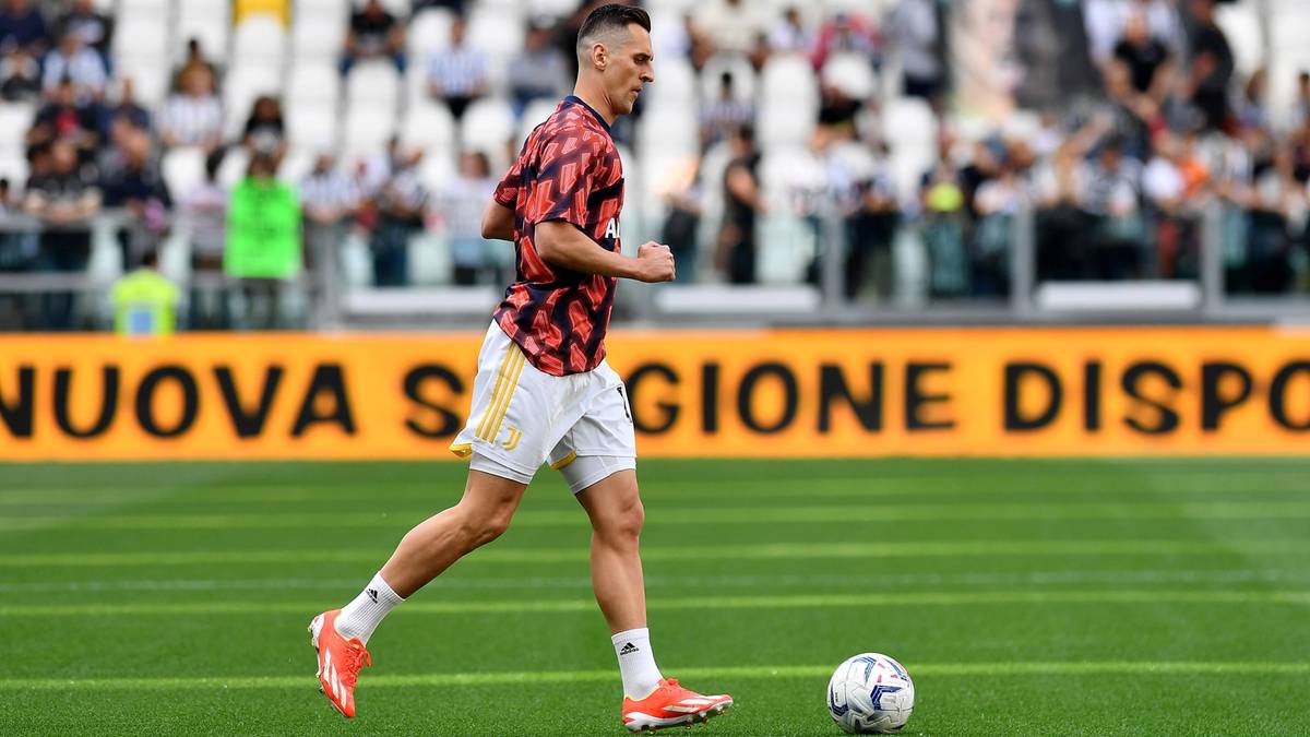 Piłkarz Juventusu biegnie z piłką na boisku.