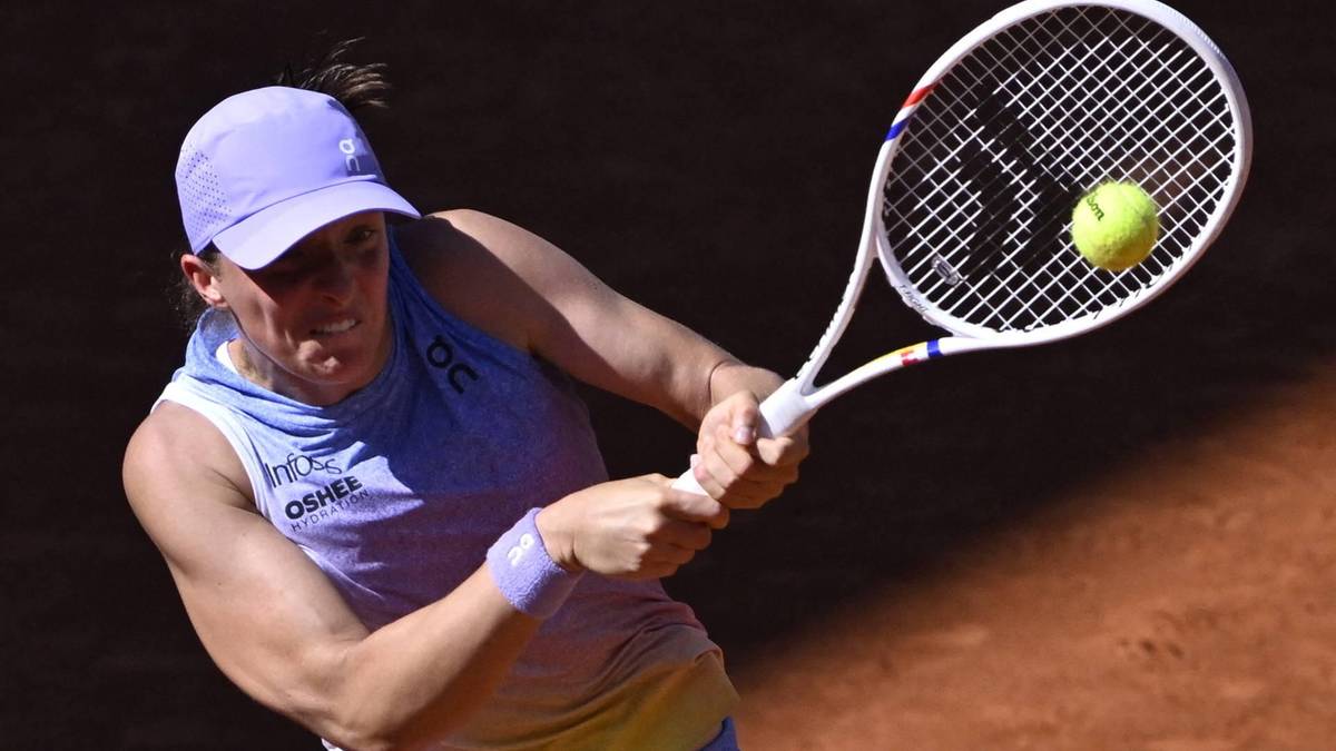 Iga Świątek podczas meczu tenisowego, z rakietą w ręku, uderza piłkę.