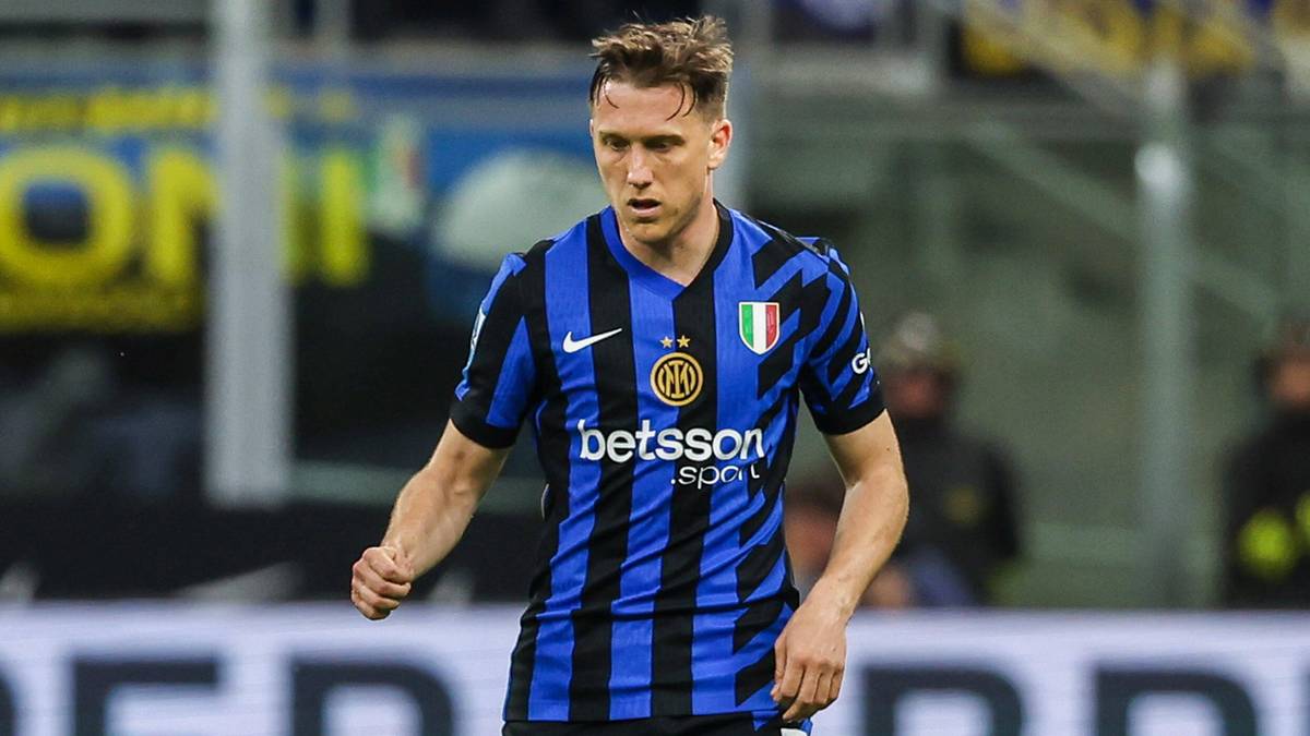 Piłkarz w niebiesko-czarnej koszulce z pionowymi pasami, na tle stadionu.