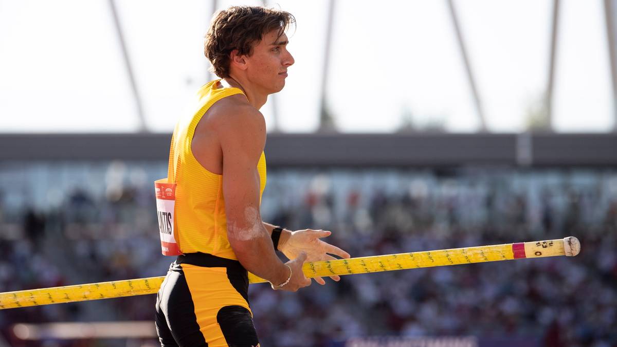 Sportowiec trzymający żółtą tyczkę, gotowy do skoku o tyczce.