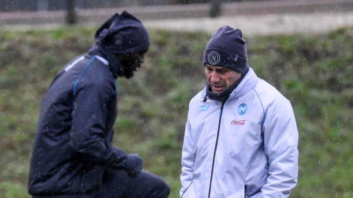 Piłkarz i trener rozmawiają na boisku.