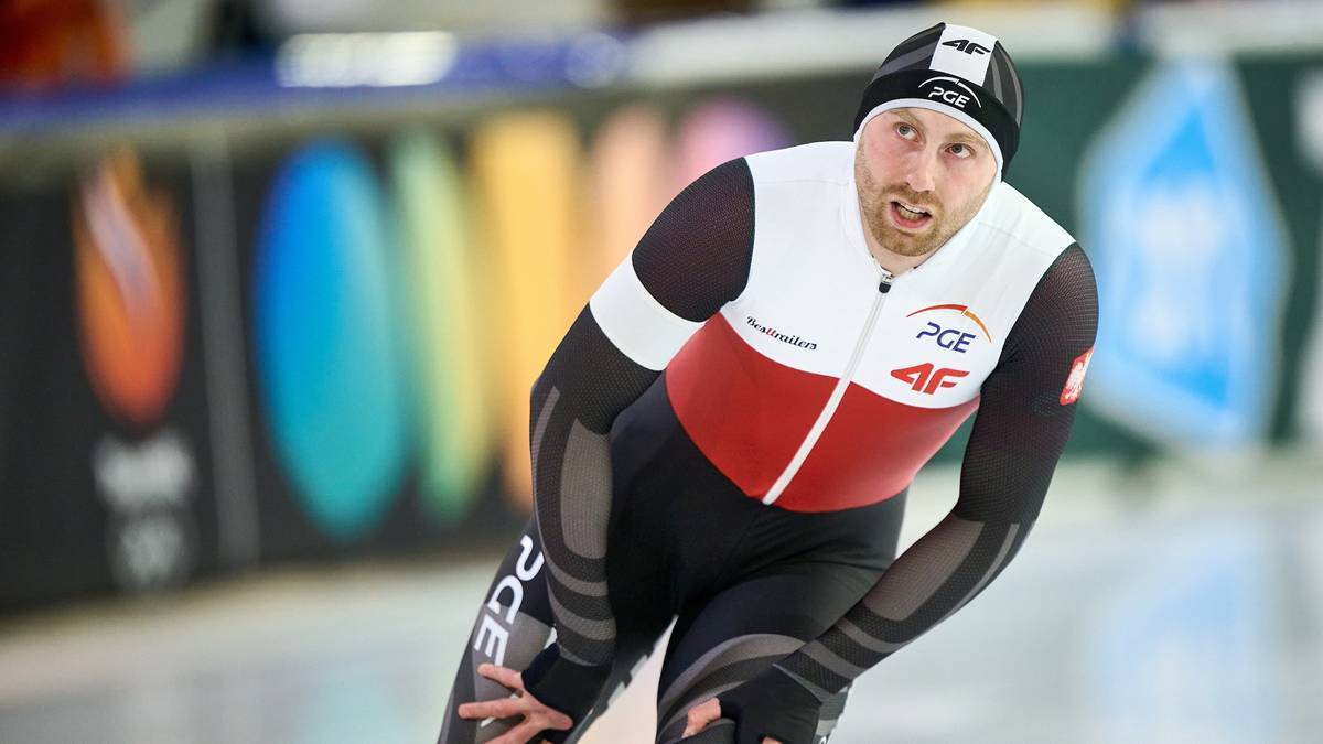 Panczenista w białoczerwonym stroju z czapką na głowie na lodowym torze