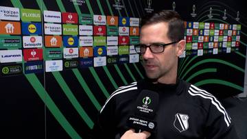 Inaki Astiz, trener, udziela wywiadu przed ścianą z logotypami sponsor&oacute;w.