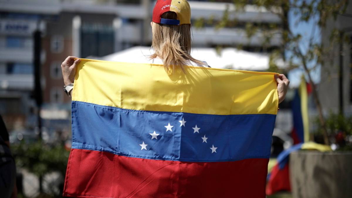 Kobieta trzyma w rękach flagę Wenezueli.