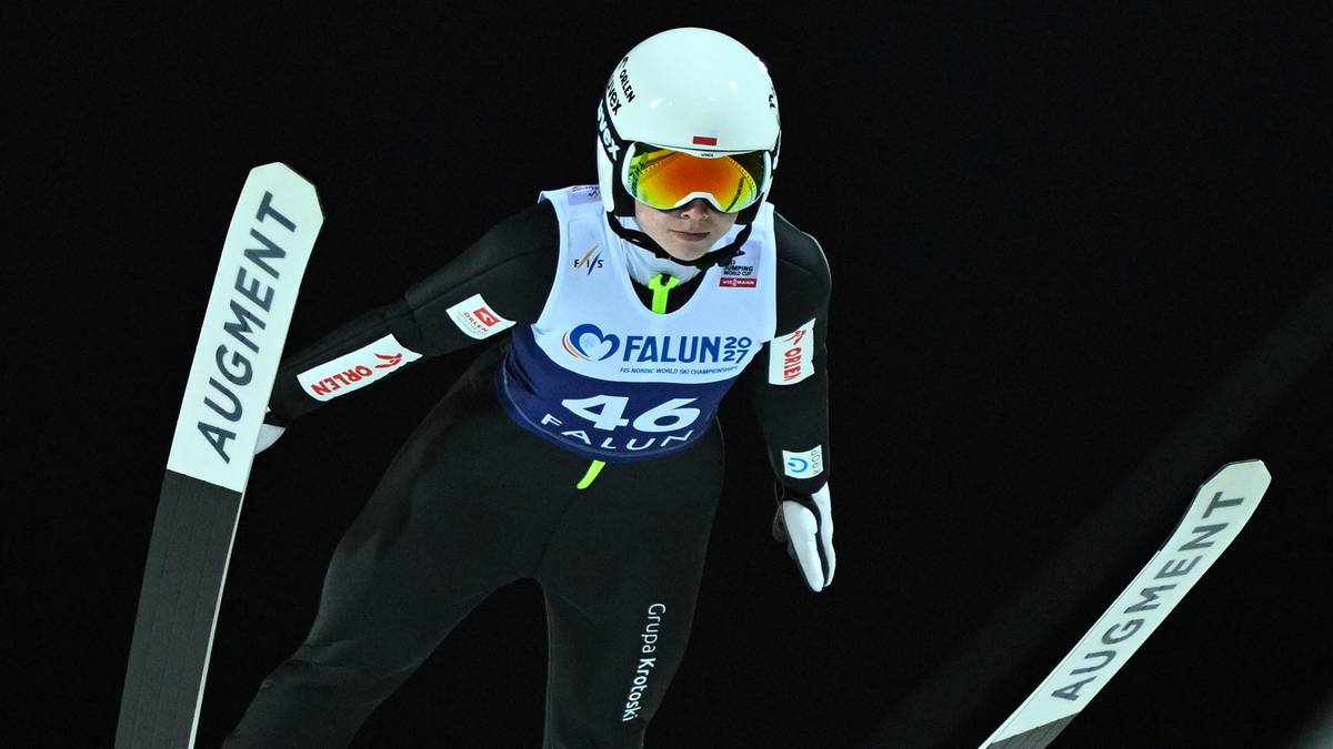 Skoczkini narciarska w białym kasku i kombinezonie z numerem 46 wykonuje skok.