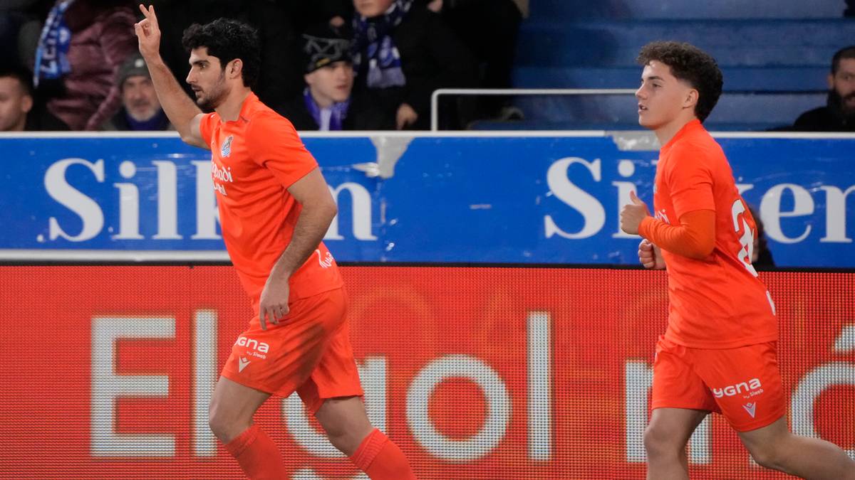 Dw&oacute;ch piłkarzy w pomarańczowych strojach świętuje zdobycie bramki, jeden z nich unosi rękę w geście zwycięstwa.