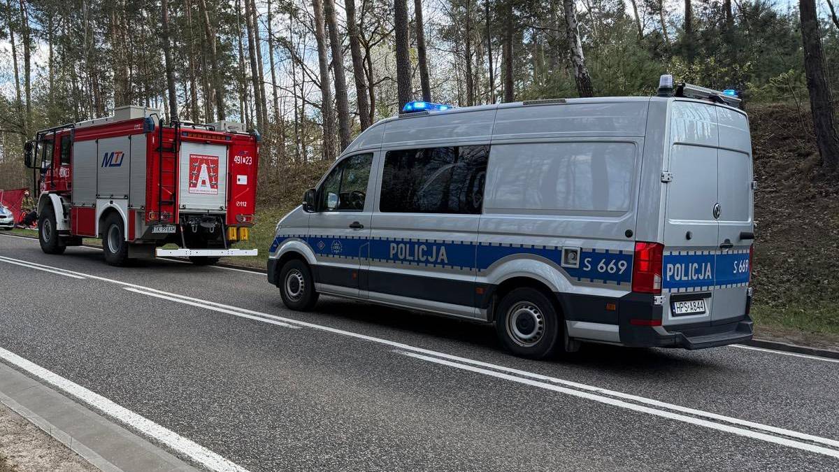 Samochody policyjne i strażackie stojące na poboczu drogi krajowej.