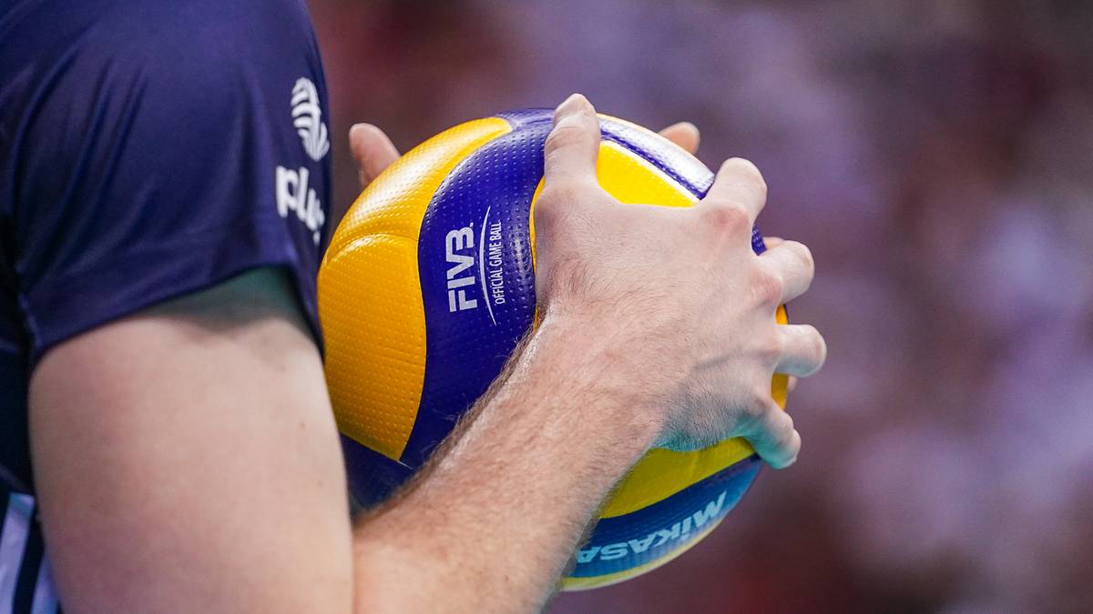 Dłonie siatkarza trzymające piłkę do siatk&oacute;wki w zbliżeniu.