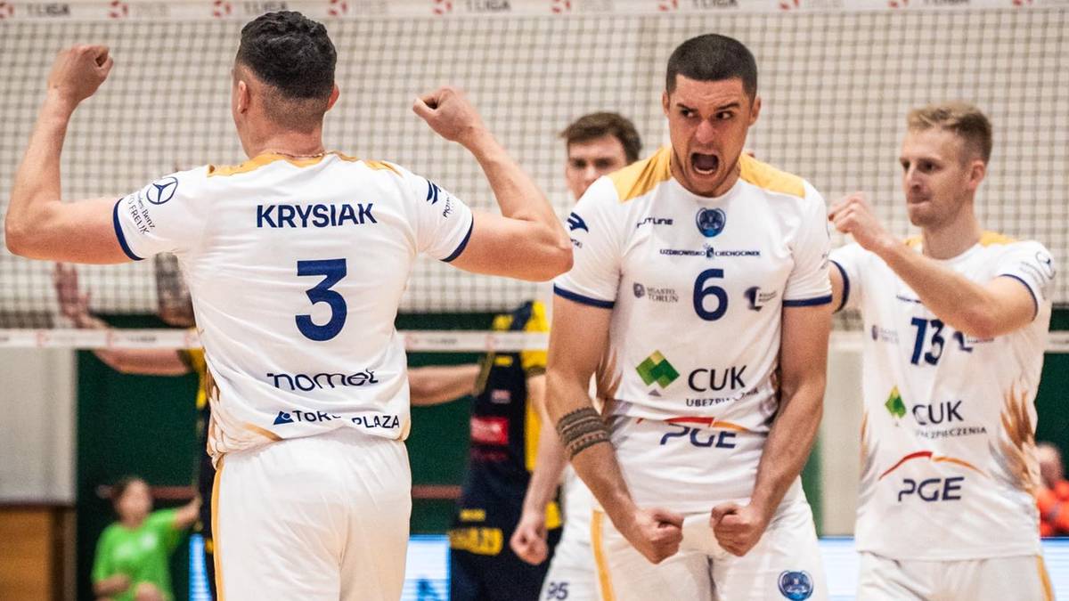 Siatkarze w białych strojach świętują zwycięstwo, jeden z nich krzyczy z radości.